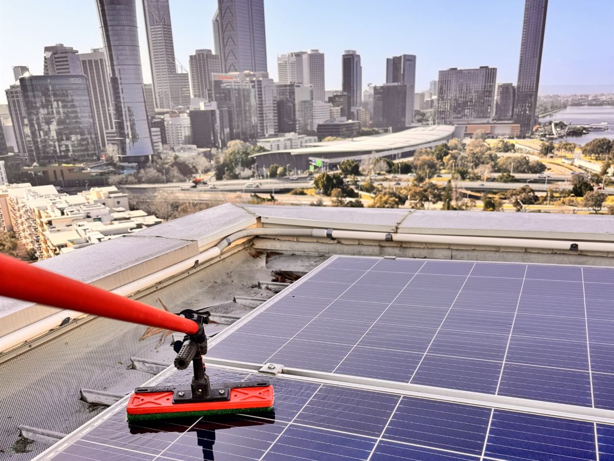 KenKleen cleaning rooftop solar panels with the Perth city skyline behind